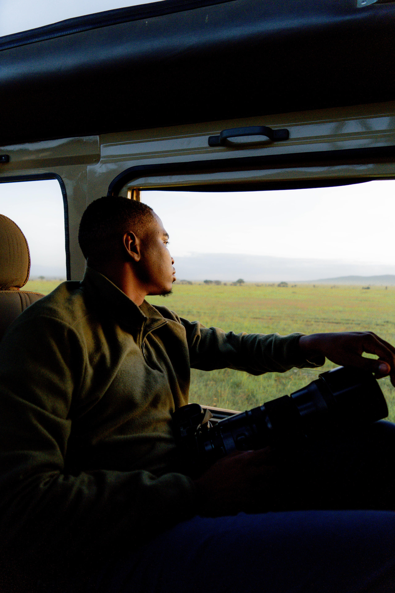 Clement Mabula watching the plains from the safari vehicle, telephoto lens in hand